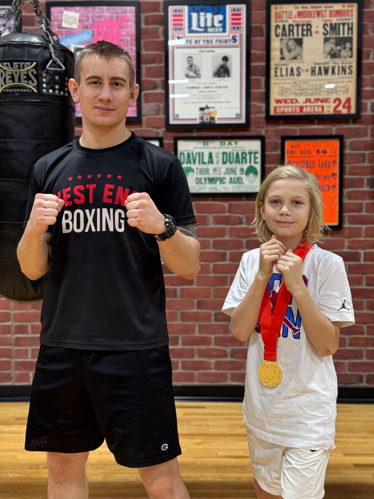 Jeremy Miazga-Grzybek, wearing a West End AC Boxing shirt standing beside James Currie who has his medal around his neck. Both are standing in fight positions.